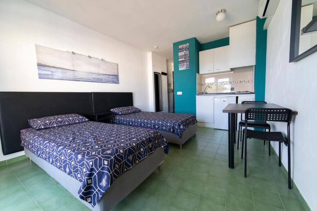 a bedroom with two beds and a table and a kitchen at Coconut Apartments - Adults Only in Magaluf
