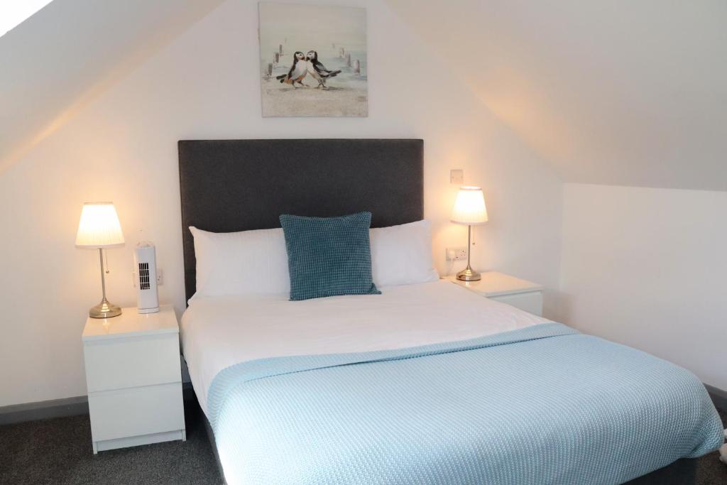 a bedroom with a large bed with two lamps at Pier12 in Eastbourne