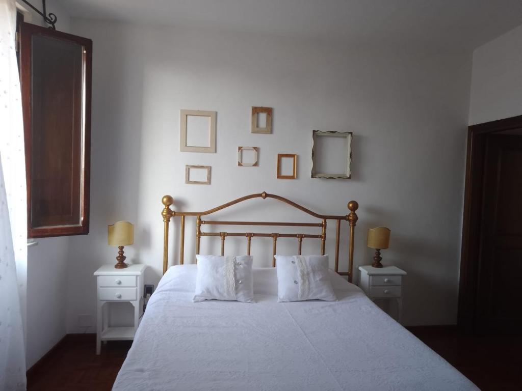 1 dormitorio con 1 cama con sábanas blancas y 2 lámparas en La Casina tra le Torri, en San Gimignano