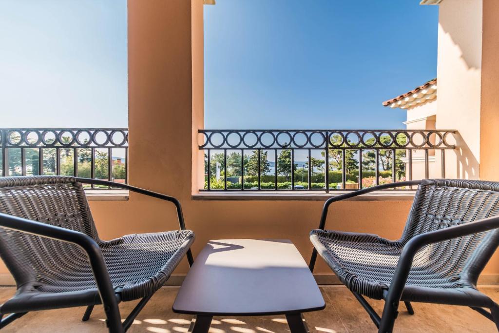 three chairs and a table on a balcony with windows at Hotel Brin d'Azur - Saint Tropez in Saint-Tropez