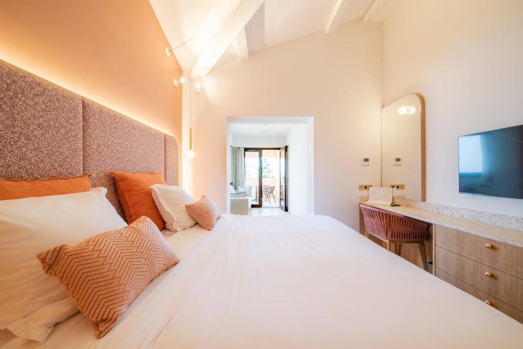 a bedroom with a large white bed and a television at Hotel Brin d'Azur - Saint Tropez in Saint-Tropez