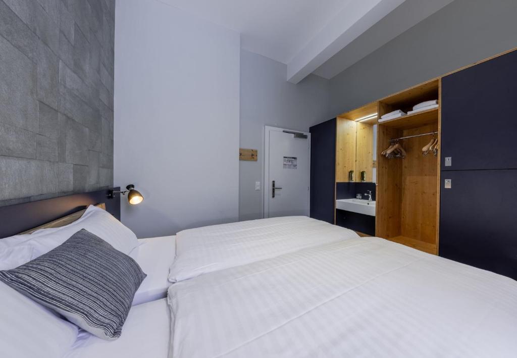 a bedroom with a large white bed and a sink at Villars Lodge in Villars-sur-Ollon