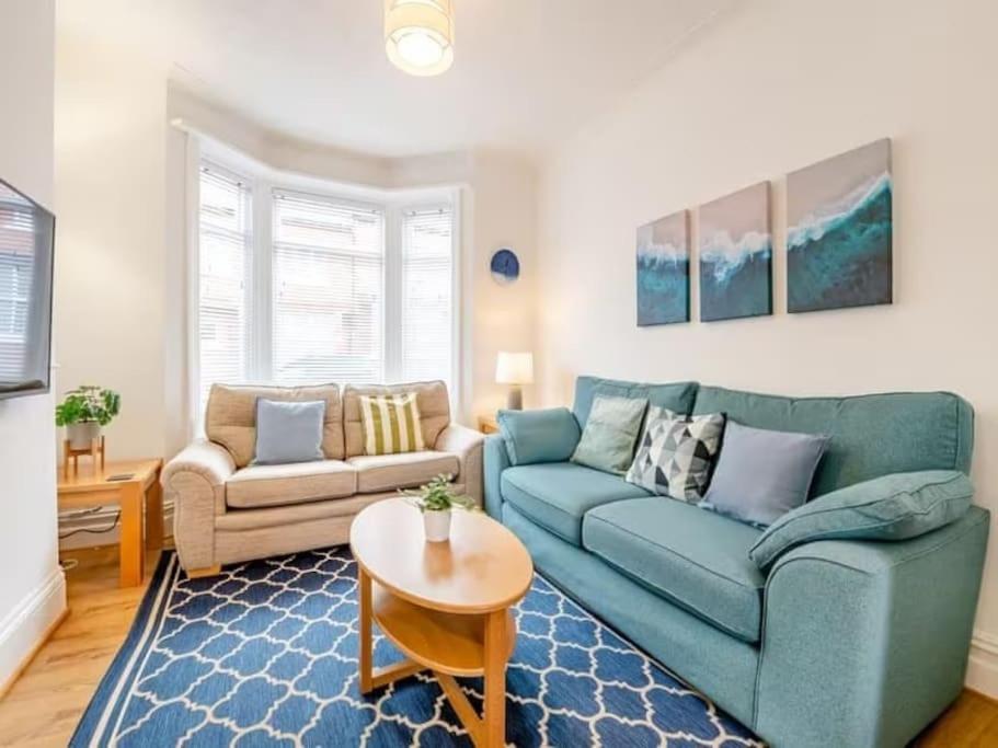 a living room with a blue couch and a table at Seagull Escapes - short walk to the beach in Scarborough