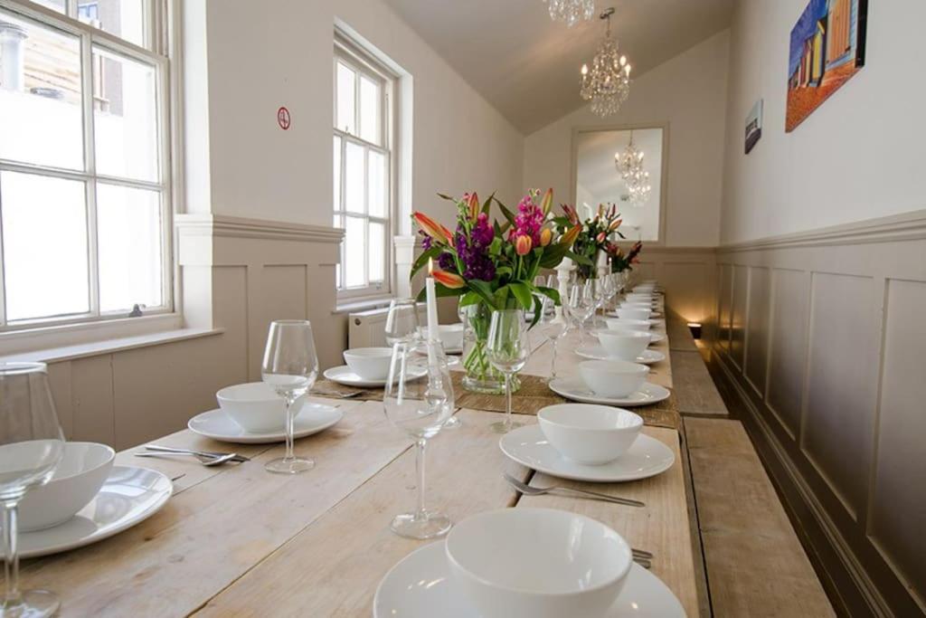 długi stół z białymi talerzami i kwiatami w pokoju w obiekcie Brighton Pavilion Gatehouse w Brighton and Hove