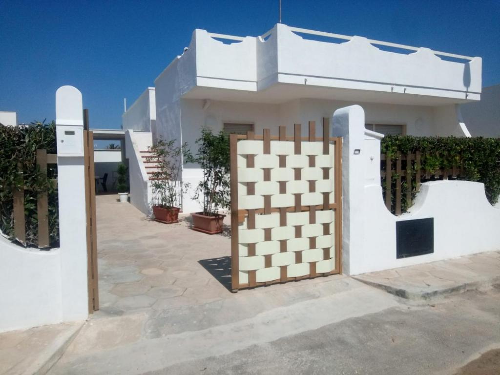 a white house with a gate and a fence at La Torre Apartment by My Home Apulia in Torre Lapillo