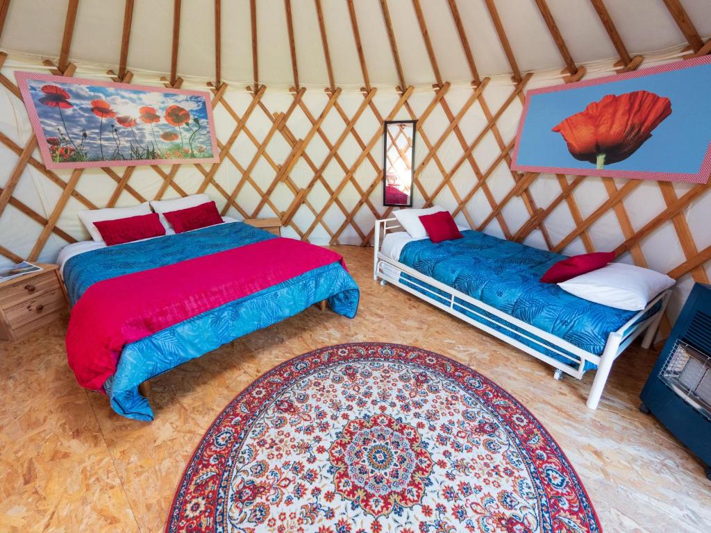- une chambre avec 2 lits et un tapis dans une yourte dans l'établissement Yourtissimo, à Laprugne