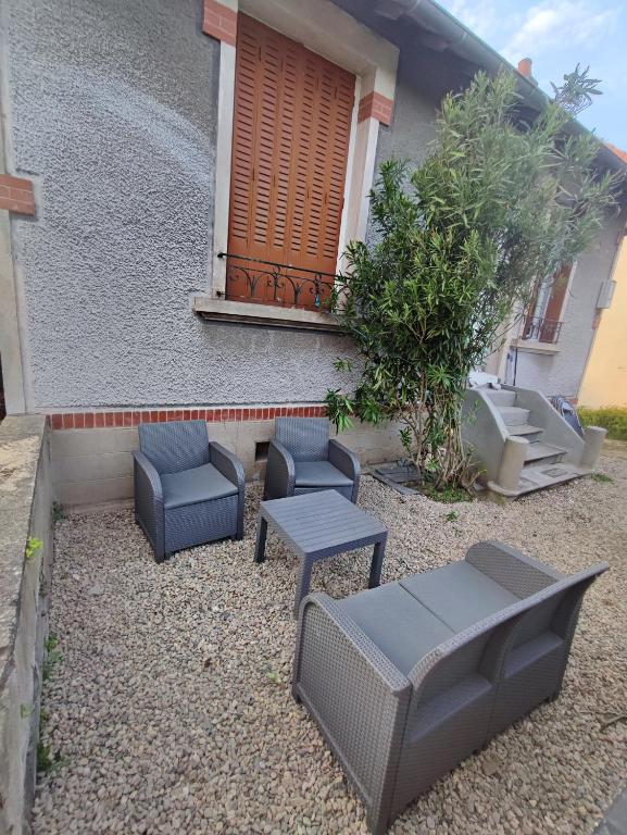 un patio avec des chaises et des tables devant un bâtiment dans l'établissement Petite maison avec jardin, à Montluçon