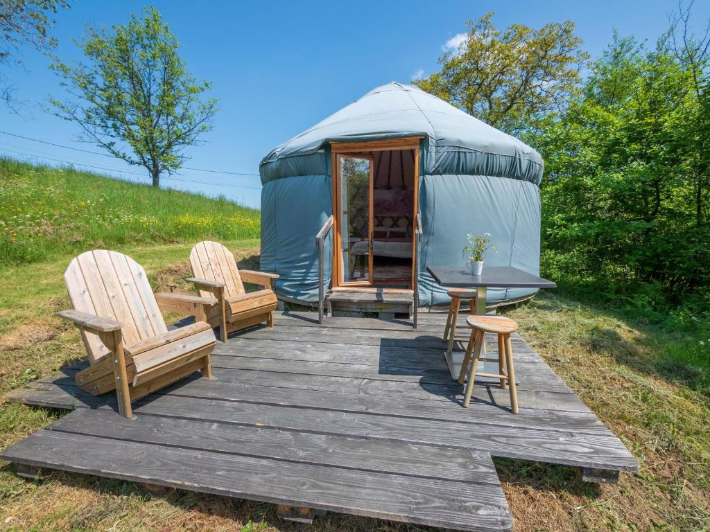 a yurt with two chairs and a table on a wooden deck at Yourtissimo in Laprugne