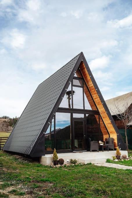 a house with a triangular roof in the grass at Casuta mea in Stulpicani