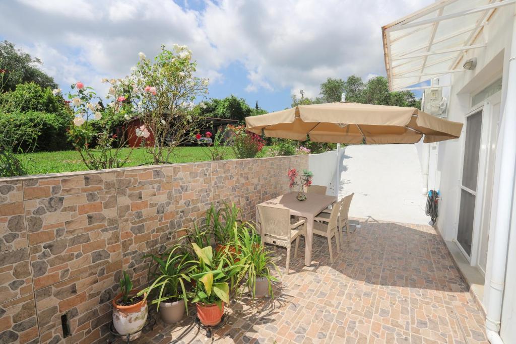 a patio with a table and an umbrella at Kassiani-Sofia Cottage 1,5 km from beach in Gouvia