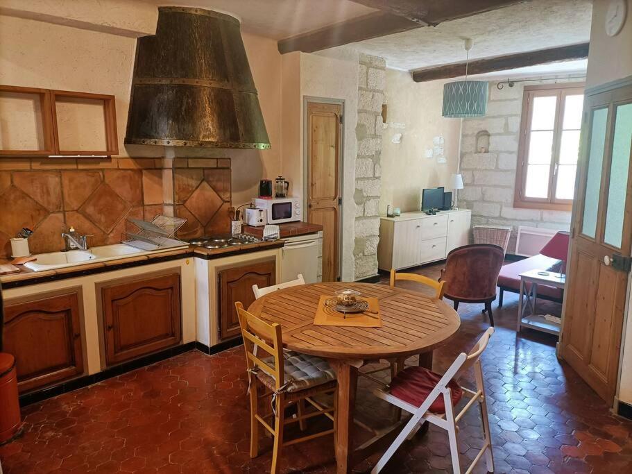 une cuisine avec une table et des chaises ainsi qu'une cuisine avec une cuisinière dans l'établissement Appartement en hyper centre La clef des chants, à Avignon