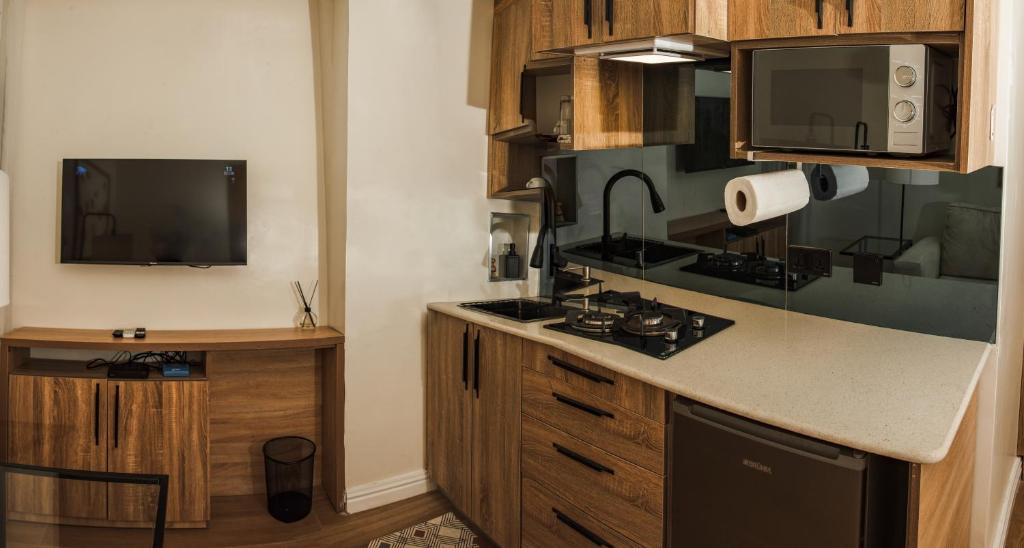 a kitchen with a stove and a tv on the wall at C. Apartments Annex in Abuja