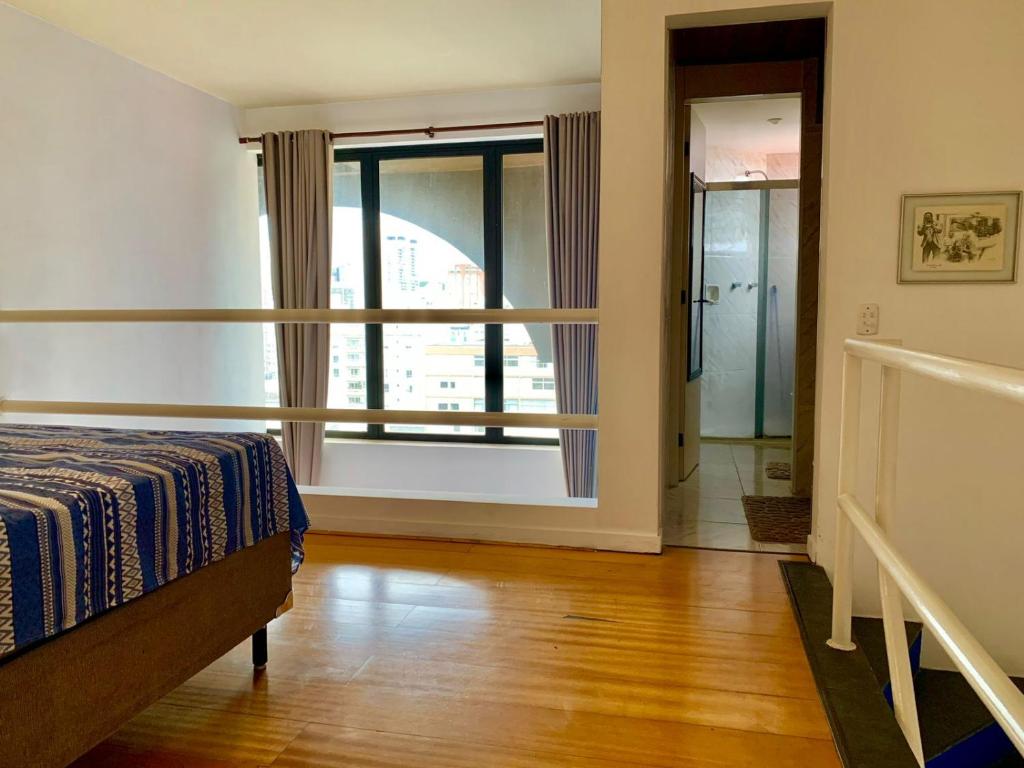 a bedroom with a bed and a large window at Belíssimo Flat em Pinheiros in Sao Paulo