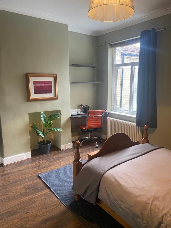 a bedroom with a bed and a desk and a chair at Tranquil Garden View Double Room in London