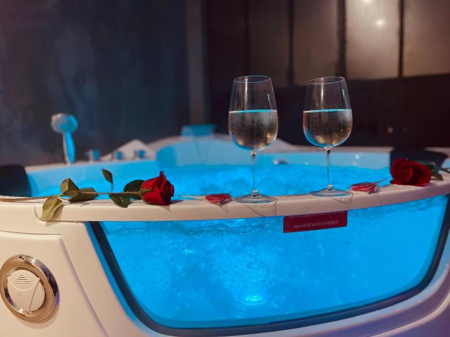 trois verres à vin sur un plateau à côté d'une piscine dans l'établissement L'Atelier des Rêves - appartement balnéo Rouen, à Rouen