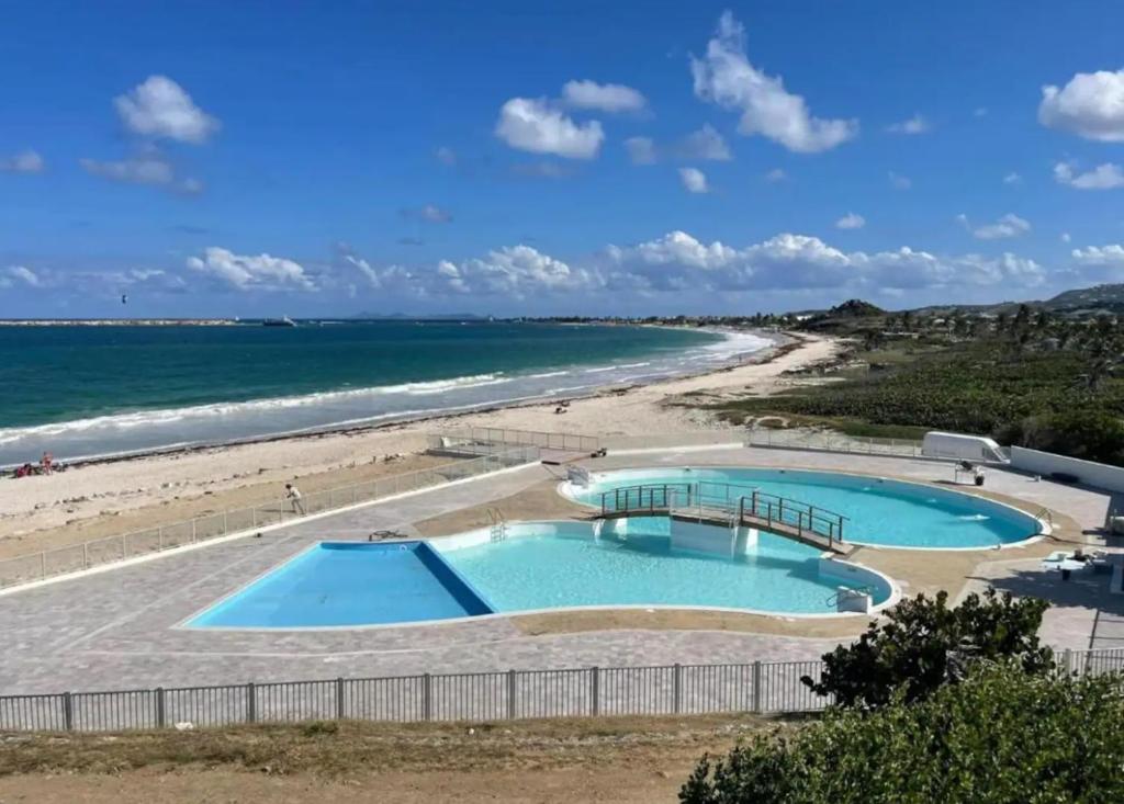 two swimming pools on a beach next to the ocean at Appartement Luxe Ocean View 9403 in Cul de Sac