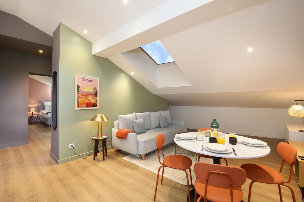 a living room with a couch and a table and chairs at Appartement calme et spacieux in Toulouse