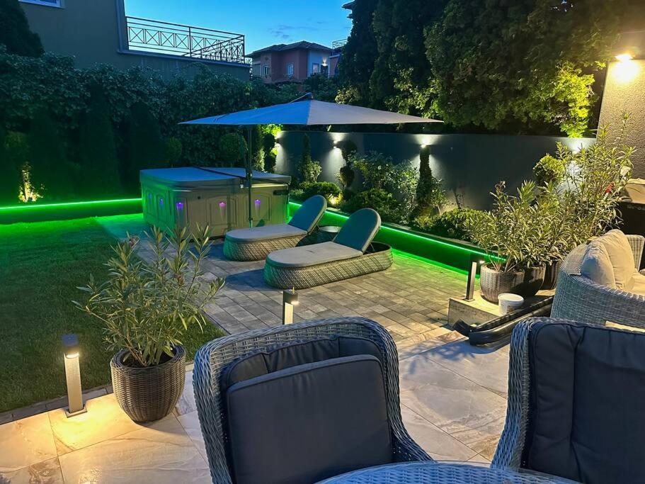 een patio met stoelen en een tafel met groene verlichting bij Oasis of Green Streamside Relaxation in Boedapest