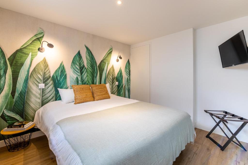 a bedroom with a large bed with leaves painted on the wall at LIK APPARTS - La Courrouze Rennes in Rennes