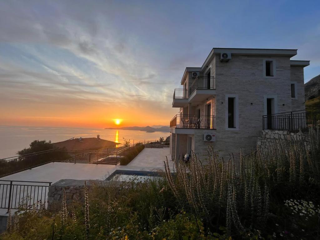 a house with the sunset in the background at Family Vacation Villa Rezevici in Budva