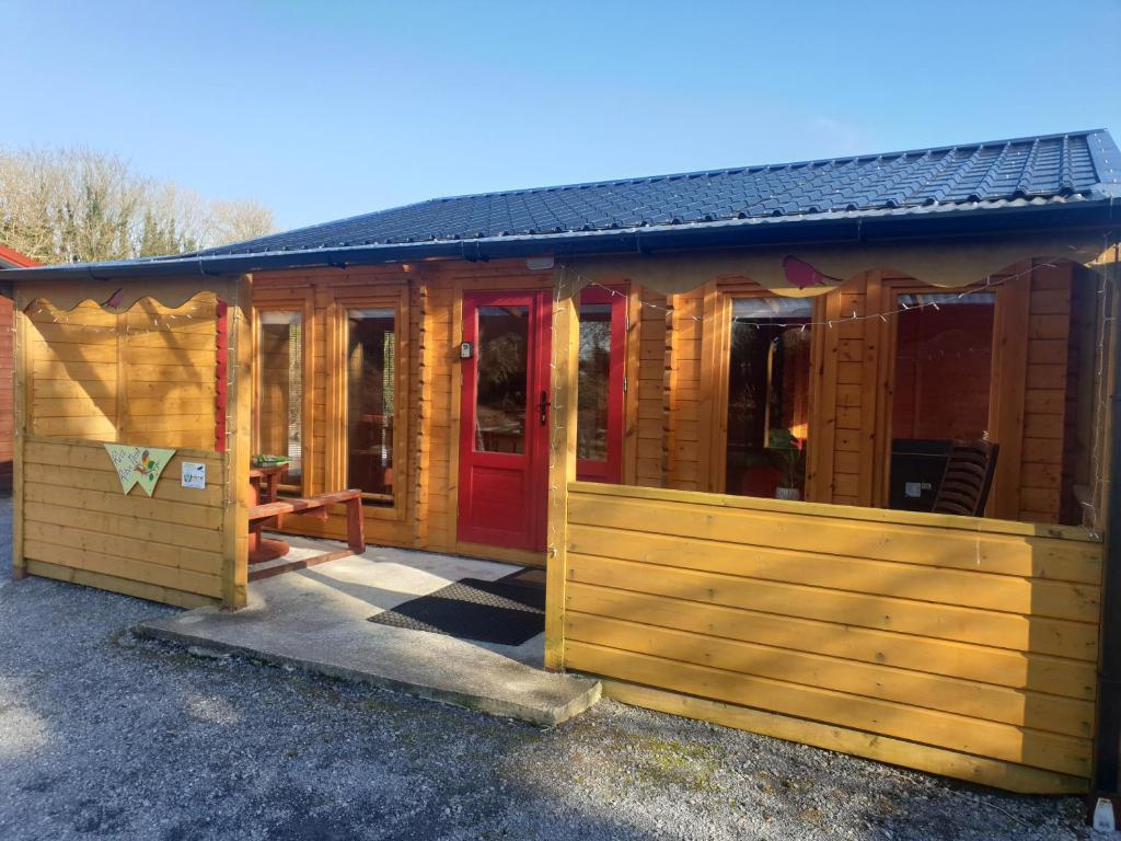 a large wooden cabin with a red door at Red Robins Nest in Galway