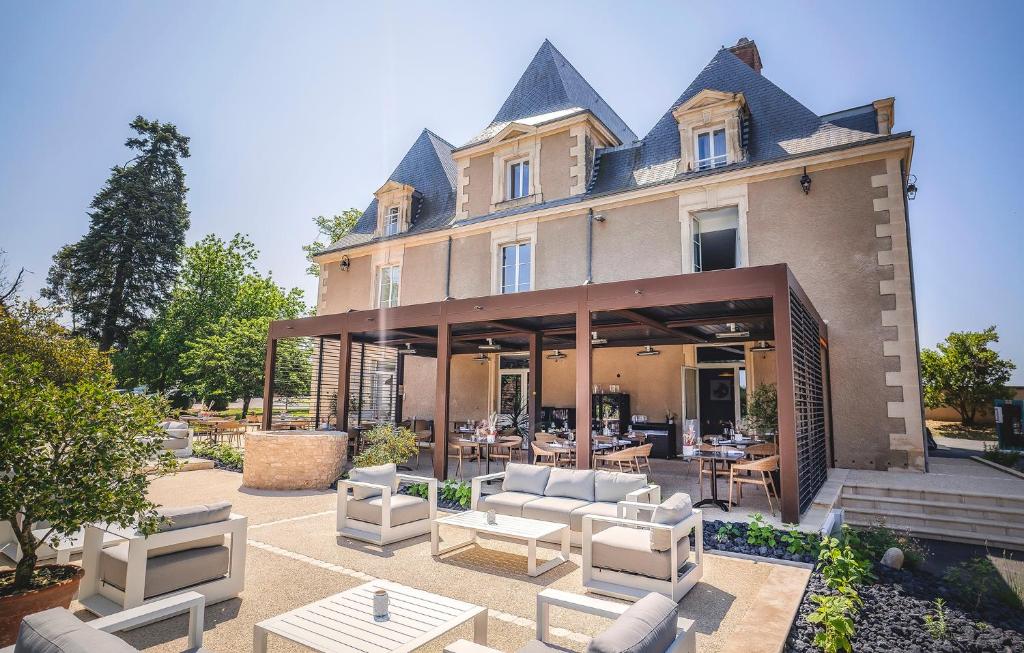 Hôtel & Restaurant - Le Manoir des Cèdres - piscine chauffée et climatisation في Rouffignac Saint-Cernin: مبنى امامه كراسي وطاولات