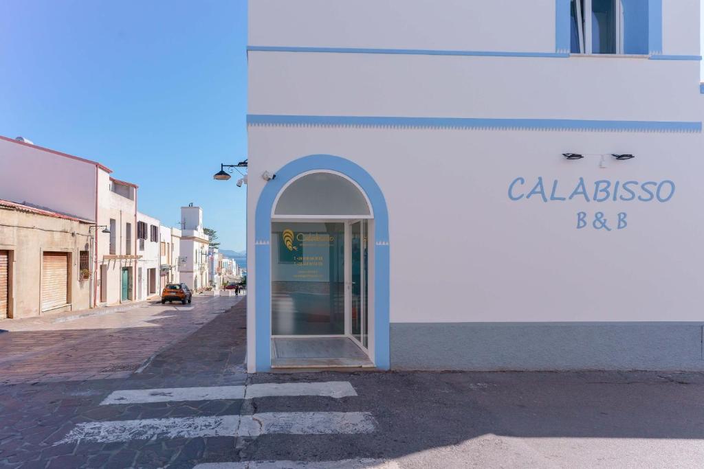 a white building with an open door on a street at CalaBisso in Calasetta