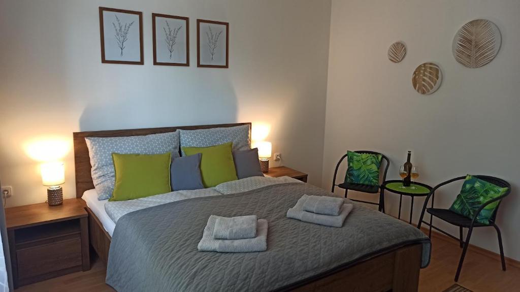 1 dormitorio con 1 cama con almohadas verdes y 2 sillas en Apartmány TriMM en Uherské Hradiště