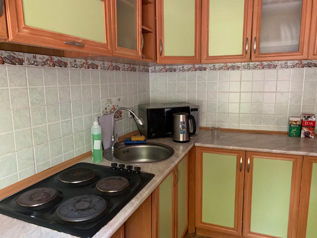a kitchen with a sink and a stove top oven at Sakura Guesthouse in Bishkek