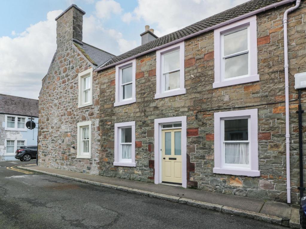 a brick house with a yellow door on a street at 30 Union Street in Kirkcudbright