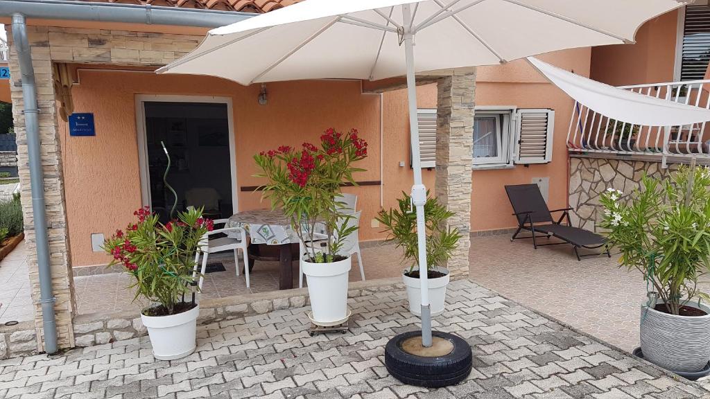 a patio with an umbrella and potted plants in buckets at Apartment Branka in Labin