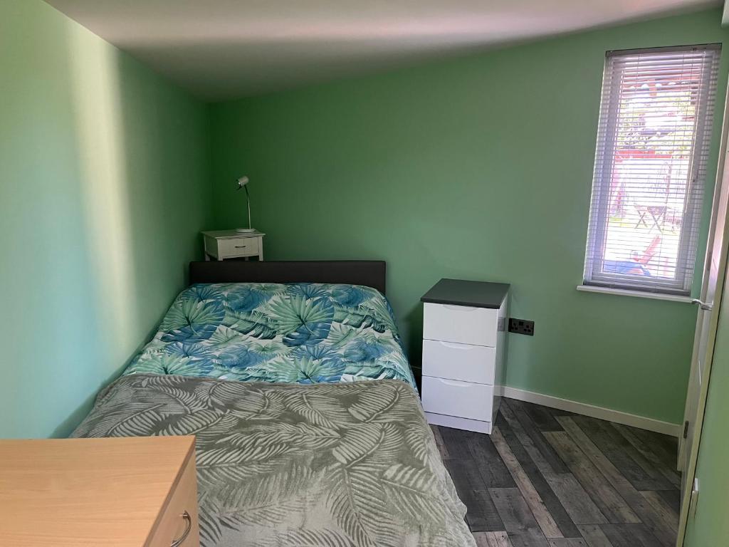 a bedroom with a bed in a green wall at Cozy room with full bathroom in Dagenham