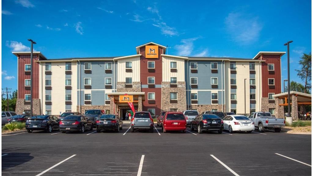 un grand bâtiment avec des voitures garées dans un parking dans l'établissement Midtown Suites - Greenville, à Greenville