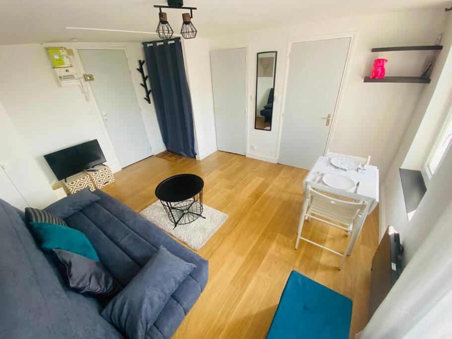 un salon avec un canapé bleu et une table dans l'établissement Le studio Aigle - proche quais rive droite - 249, à Rouen