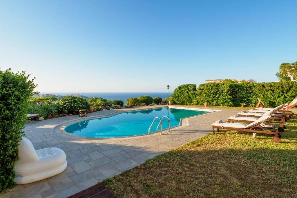 een zwembad met stoelen en de oceaan op de achtergrond bij Wild Pear Villa in Agia Pelagia