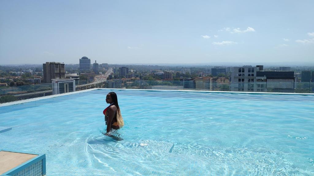 a woman standing on the edge of a swimming pool on a building at Skynest Residences by Lisa's Paradise B in Nairobi