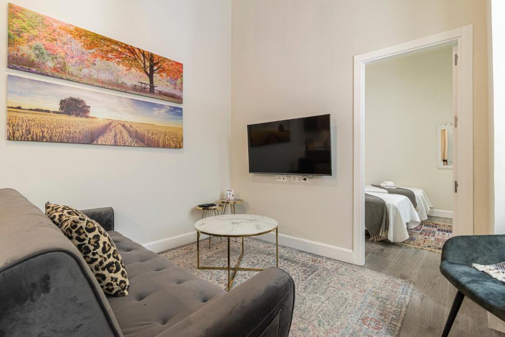 a living room with a couch and a tv at Casa Palacio Rufina & Jardines in Jerez de la Frontera