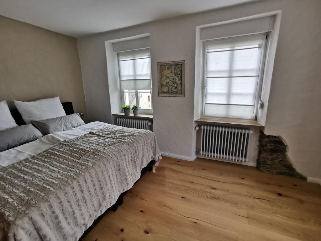 a bedroom with a large bed and two windows at Das Kirch24 - DAS Ferienhaus in Heidenburg in Heidenburg