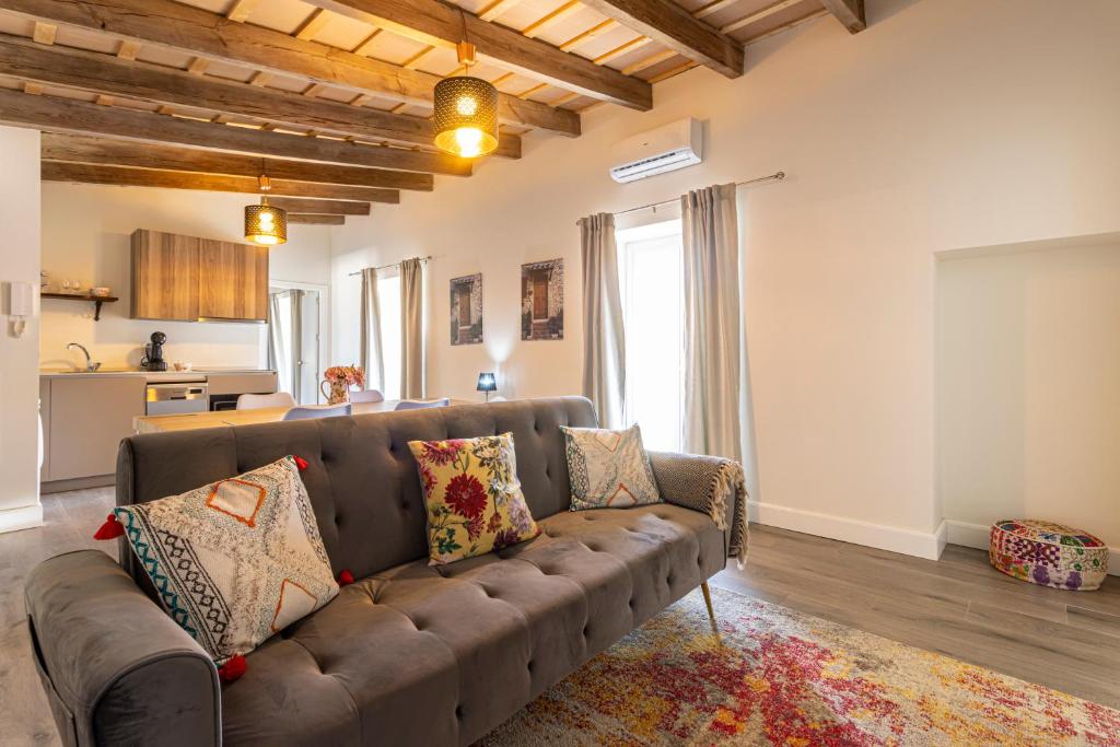 a living room with a brown couch and a kitchen at Casa Palacio Rufina & Jardines in Jerez de la Frontera