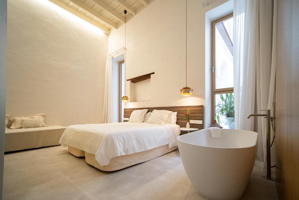 a white bedroom with a bed and a tub in it at Apartamentos Alcoba 13 in Sanlúcar de Barrameda