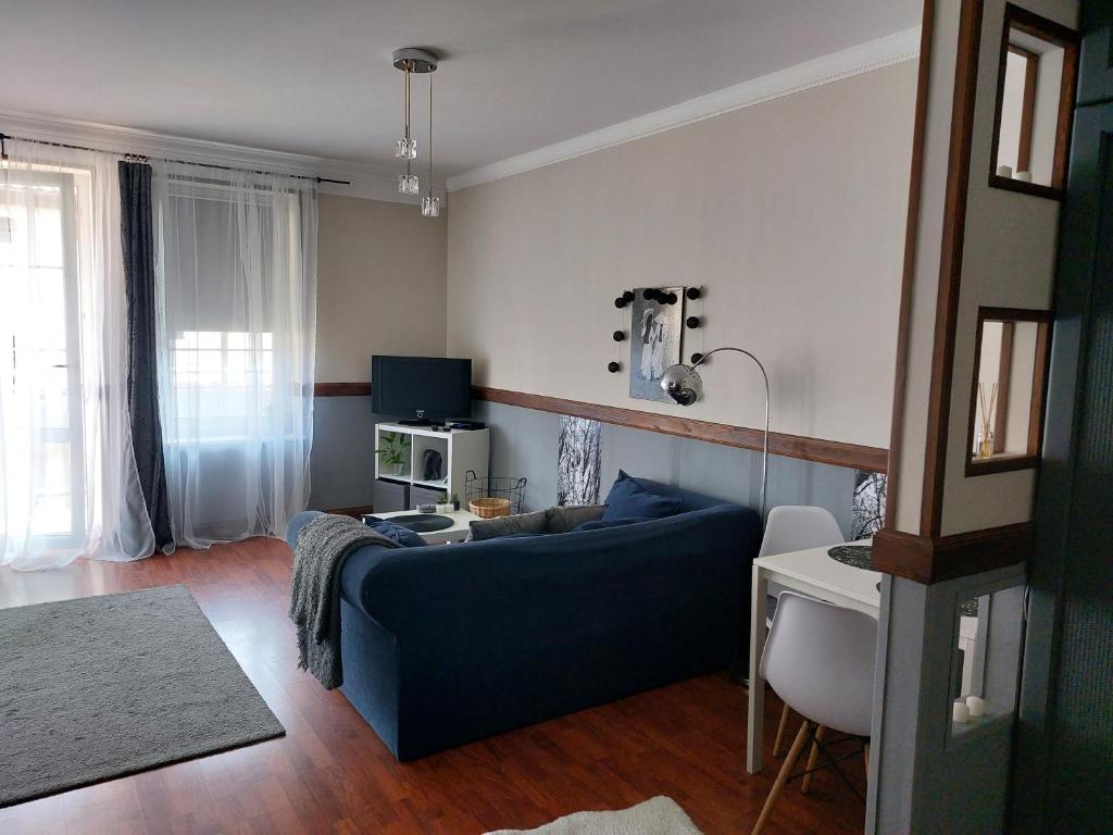een woonkamer met een blauwe bank en een tafel bij Apartament Radosna in Gdynia