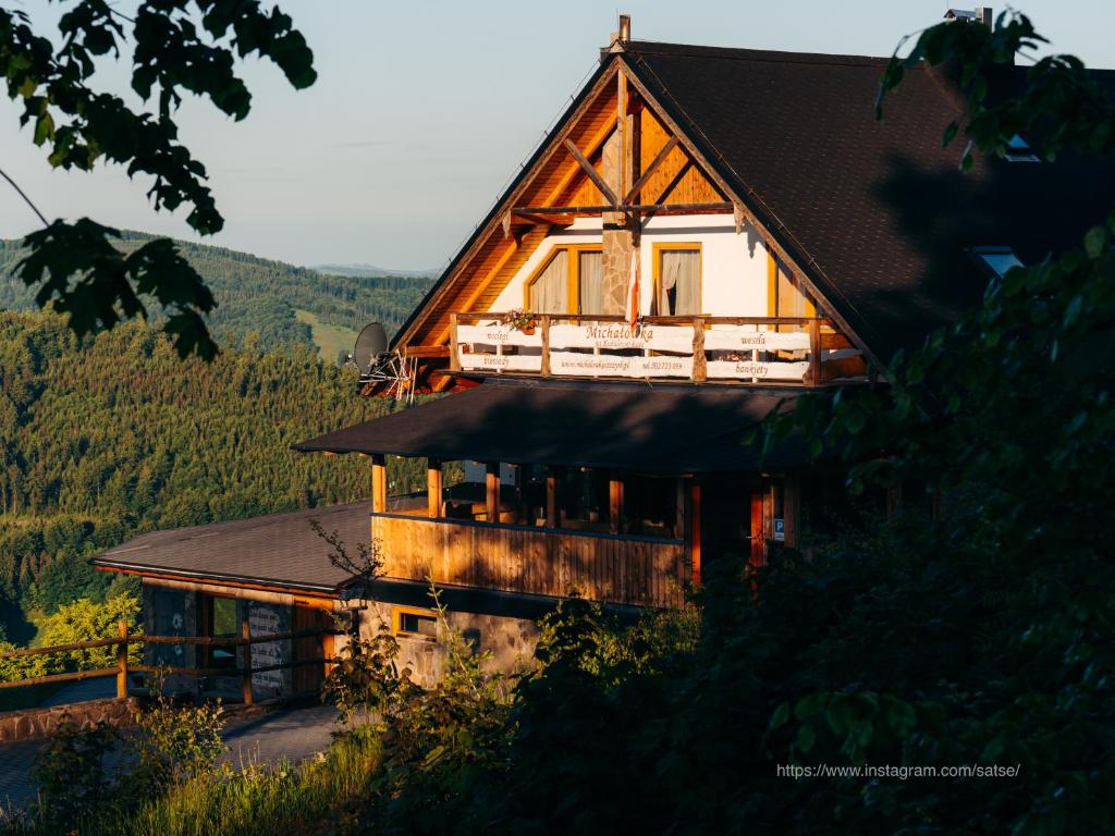 ein Holzhaus mit schwarzem Dach in der Unterkunft Michałówka na Kubalowej Łące in Szczyrk