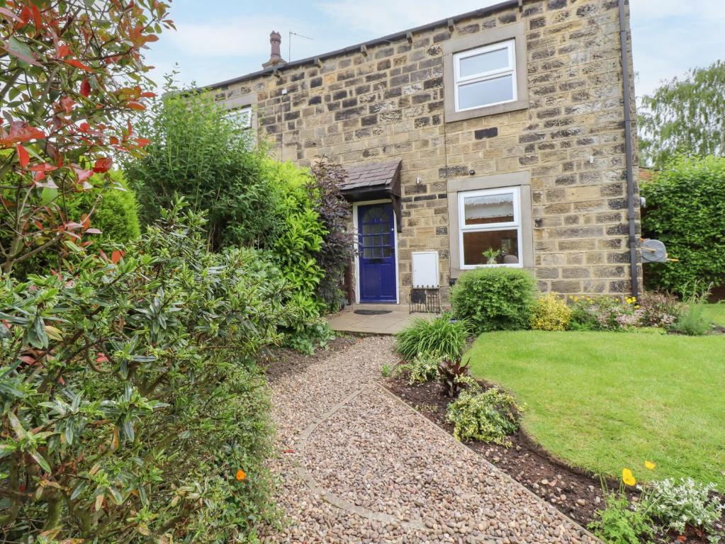 a stone house with a blue door and a yard at 1 The Old Chapel in Otley