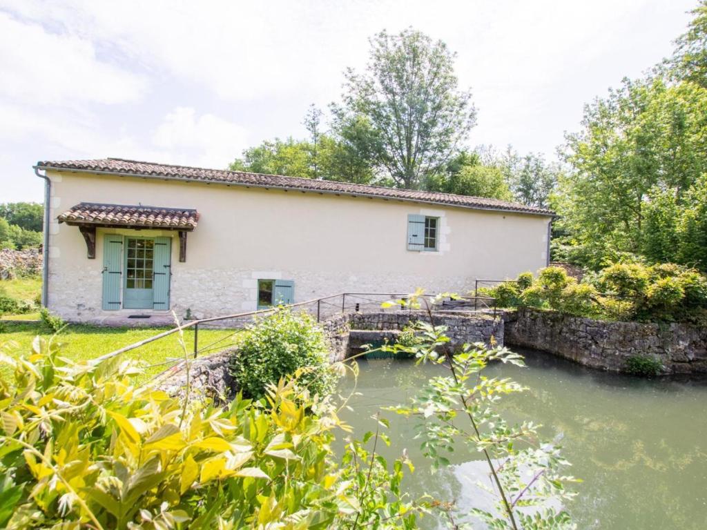 una casa con un río delante de ella en Moulin Périgourdin : 3 Chambres, Jardin, Rivière et Activités Familiales - FR-1-616-324, en Conne-de-Labarde