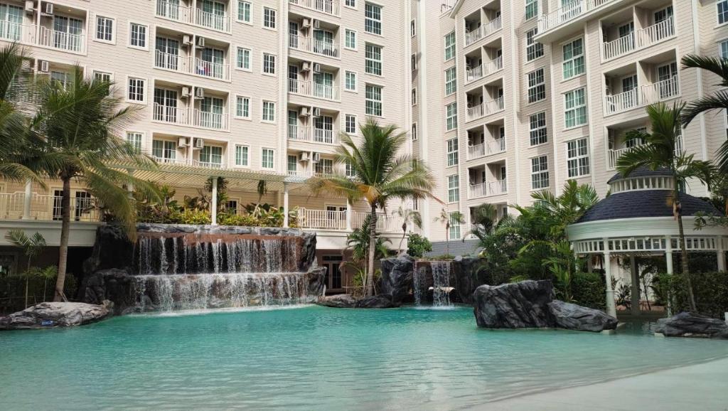uma cascata no meio de uma piscina com edifícios em Grand Florida BeachFront Resort NaJomtien Pattaya em Na Jomtien