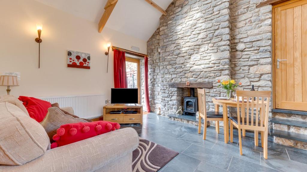 a living room with a couch and a stone wall at The Stable, Llanmadoc in Llanmadoc
