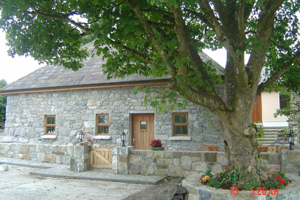 ein Steinhaus mit einem Baum davor in der Unterkunft Traditional Stone Cottage 300 years+ in Galway