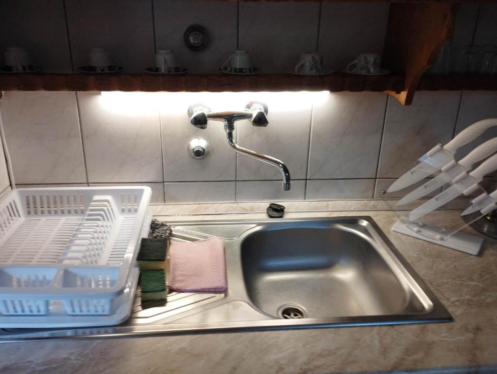 um lavatório de cozinha com um suporte para secar pratos ao lado em Nóra Vendégház em Abádszalók