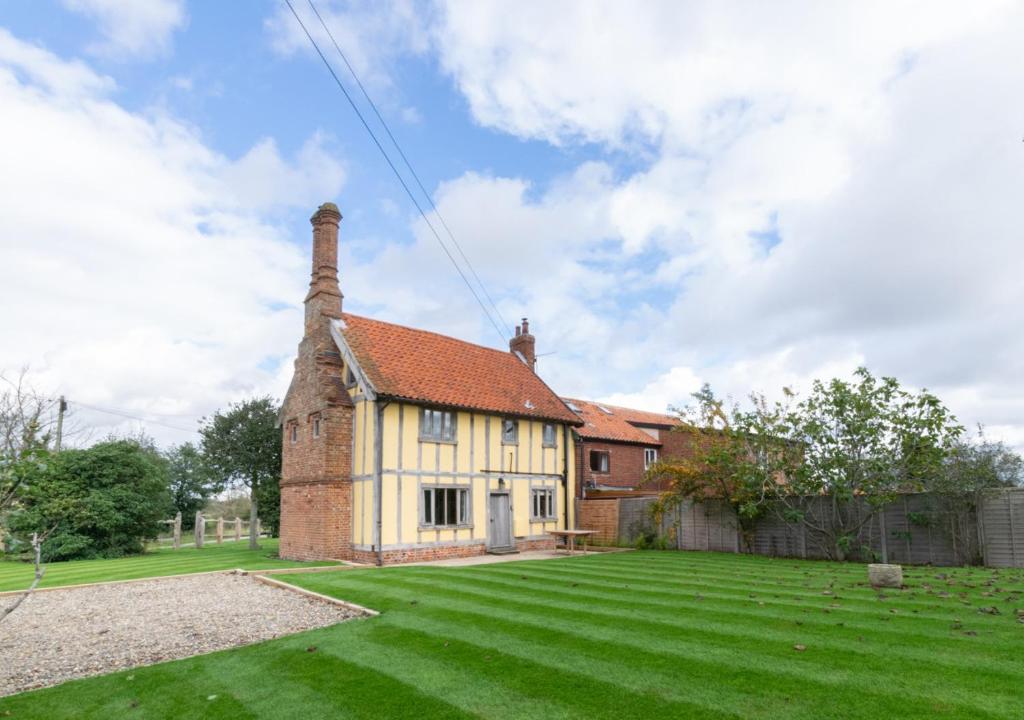 uma antiga casa de tijolos com um grande quintal em Stone Cottage em Darsham