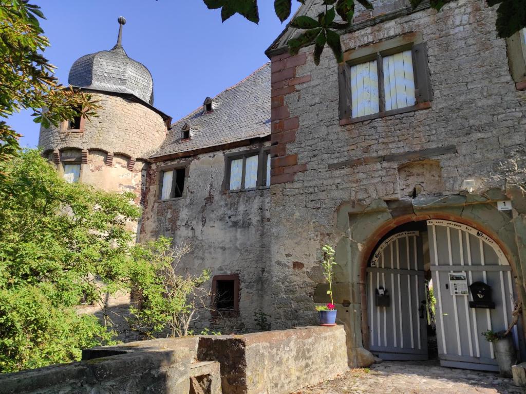 una antigua casa de piedra con una gran puerta y una torre en Schloss Höllrich en Karsbach